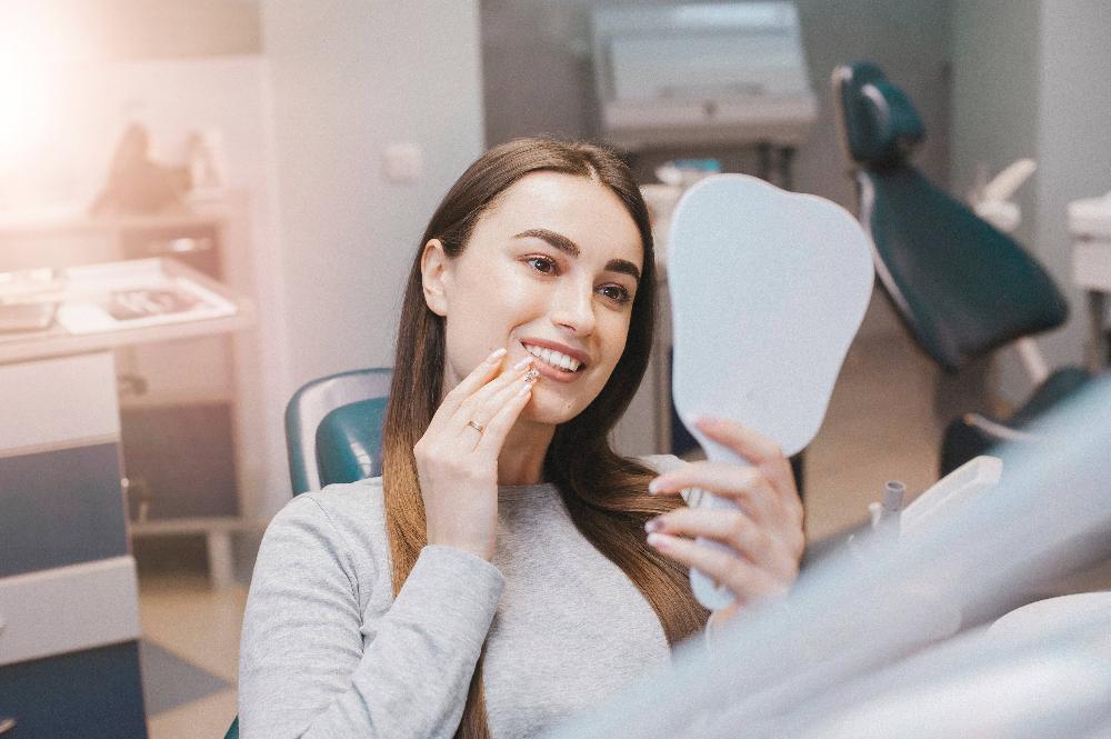 Patient looking at teeth in a mirror at dentist office in Apex NC